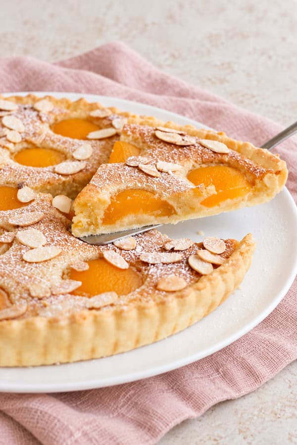 Gros plan sur une part de tarte amandine aux abricots, montrant la crème d’amande fondante et les abricots.