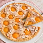 Tarte amandine aux abricots sur assiette blanche.