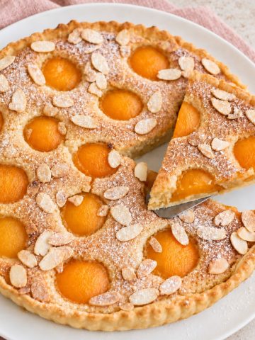 Tarte amandine aux abricots sur assiette blanche.
