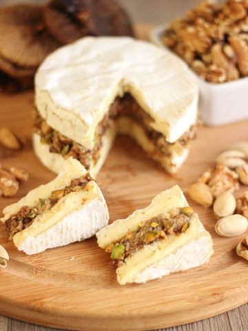 Camembert farci aux noix, pistaches et figues sur planche à découper