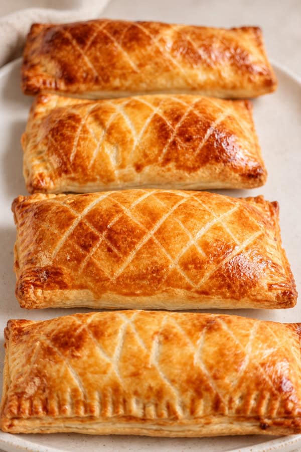 Quatre Friands dorés au jambon, fromage et béchamel sur une grande assiette blanche.