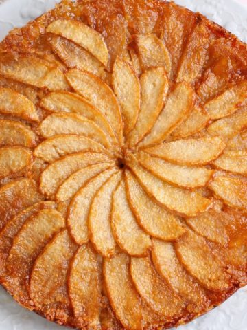 Gâteau aux pommes caramélisées sur assiette blanche.