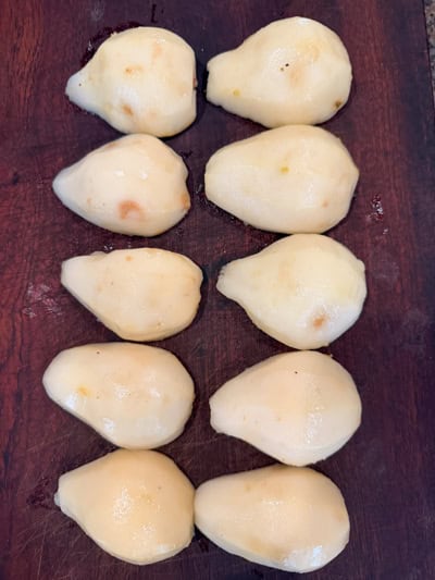 Demi-poires épluchées disposées sur une planche à découper en bois.