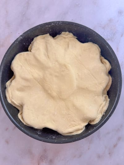 Pâte feuilletée recouvrant les poires, avec les bords rentrés à l’intérieur du moule.